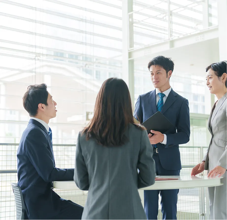 ビジネスの現場でチームメンバーが円卓に集まりプロジェクトの課題解決に向けて活発な議論や情報共有を重ねるオフィス風景
