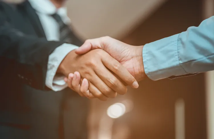 税務相談や顧問契約の締結を象徴するスーツ姿の専門家とクライアントが信頼を込めて握手を交わす安心感のあるビジネス風景